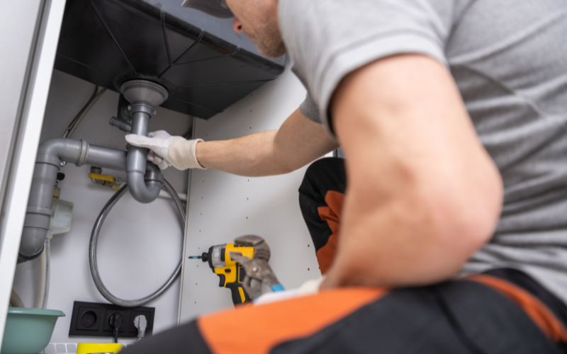 Plumber using a snake tool to fix a clogged drain.